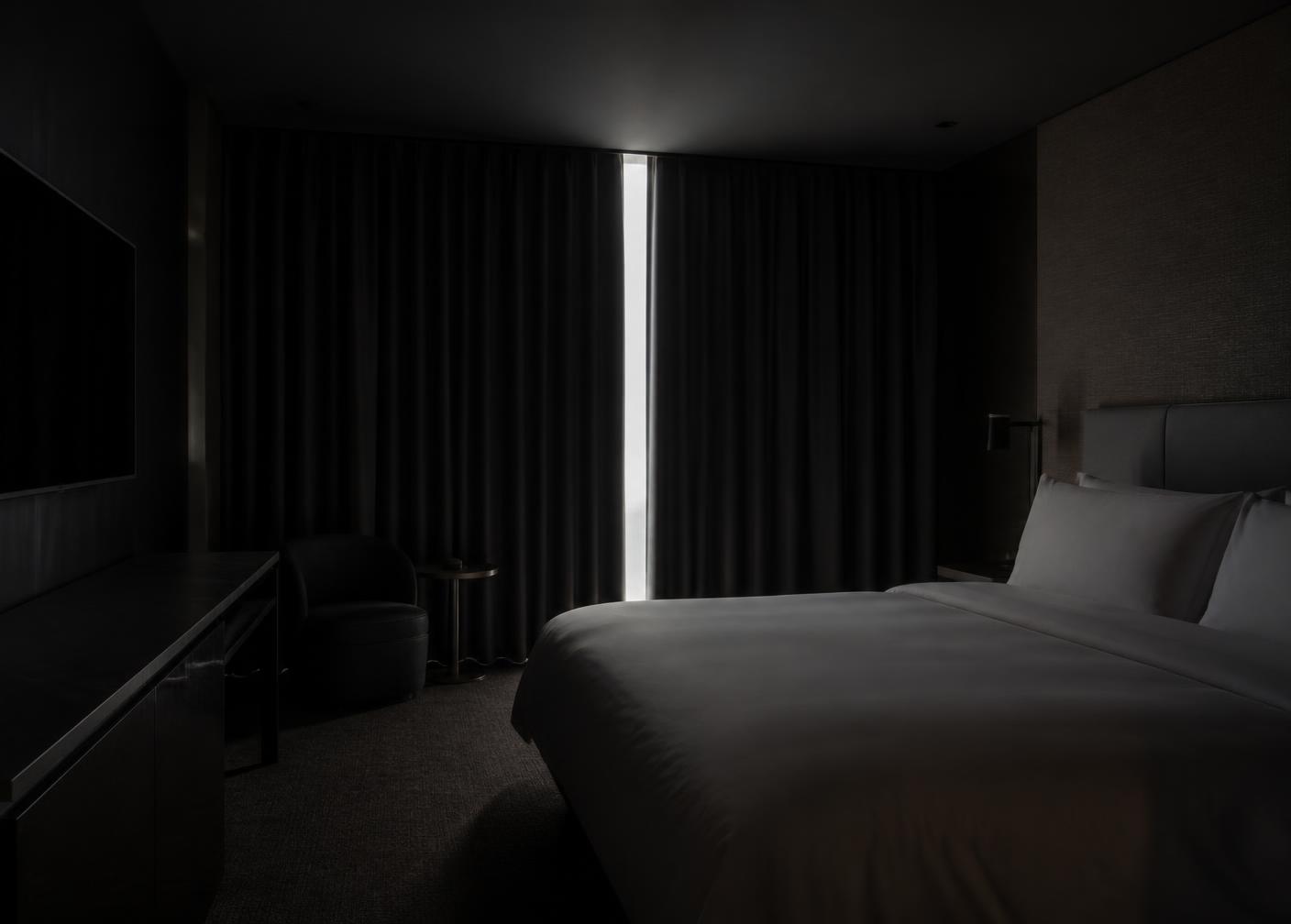 Darkened hotel guestroom with blockout curtains drawn across the window