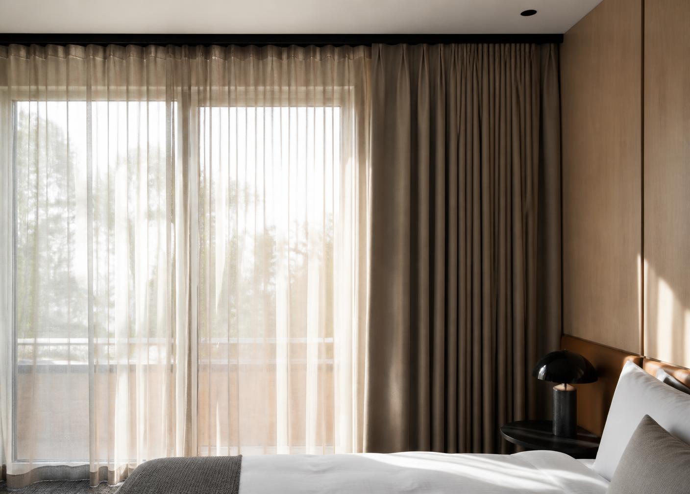 Layered sheer and blockout hotel curtains on a slim ceiling track